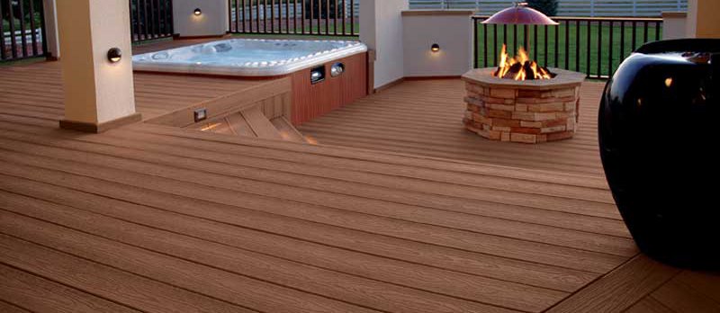 Exceptional area of a house with composite deck boards, a fire pit, sitting area, and a hot tub