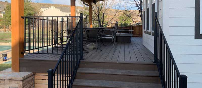 A Trex patio decking made wooden from the top and rails outside of a house with chairs and tables 