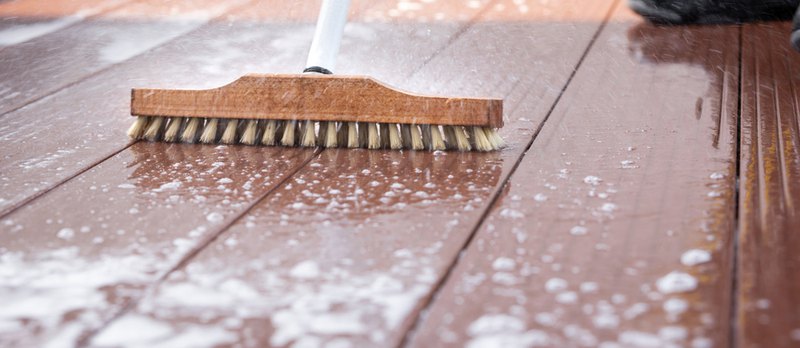 Detail brushing off a deck; you can learn how to clean a Trex deck without a power washer.